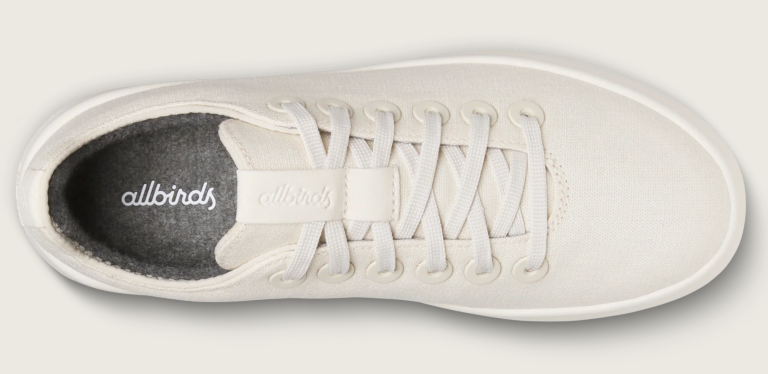 White lace-up sneaker with a textured surface and grey interior.